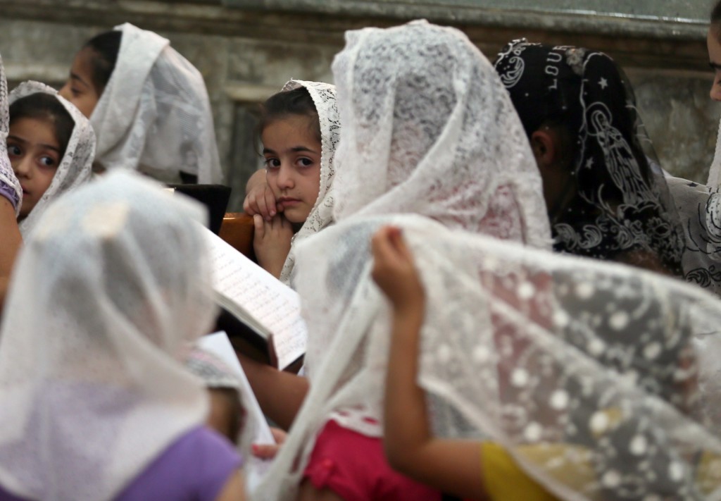 Bambine irachene cristiane pregano nella chiesa della Vergine Maria nella cittadina di Bartala, a est di Mosul.  (Afp/Karim Sahib)